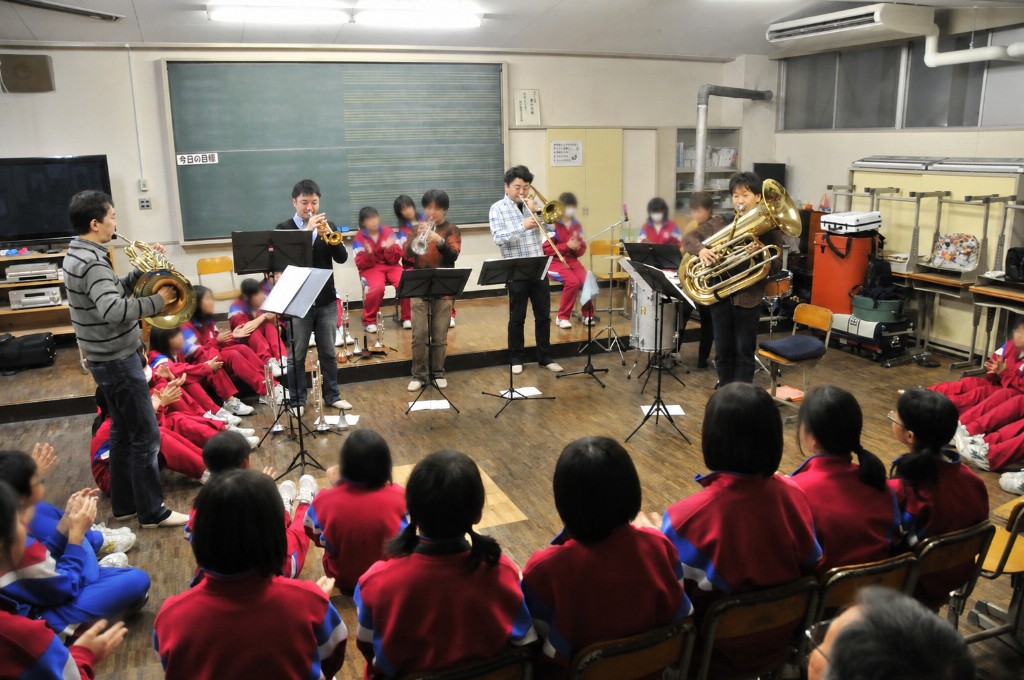中学校・小学校の音楽室で金管五重奏が取り囲まれるように児童に演奏している様子
